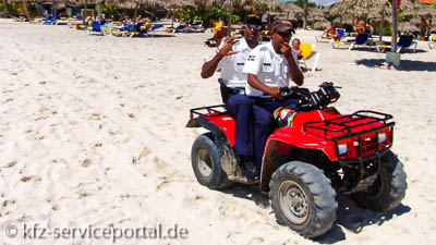 Ein Quad mit zwei Polizisten an einem Sandstrand in der Dominikanischen Republik