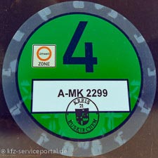 In einer Frontscheibe eines Fahrzeugs klebt eine grüne Umweltplakette.