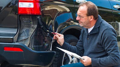 Ein Sachverständiger begutachtet einen Unfallwagen und stellt Beweise sicher