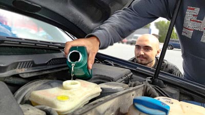 Ein Mechaniker füllt Bremsflüssigkeit in den Behälter im Motorraum