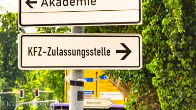 Ein Straßenschild zeigt mit einer Aufschrift den Weg zur Kfz-Zulassungsstelle.