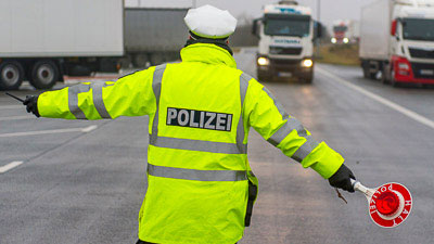 Ein Polizist weist einen LKW zur Kontrolle ein.