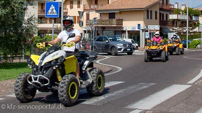 Mehrere Quads fahren auf einer Straße.
