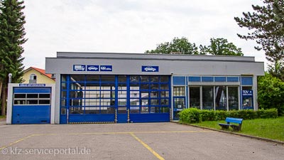 Blick auf die Halle einer Prüfstelle. Über den Toren sind die Fahrzeugtypen zu erkennen, auch der Wohnwagen.