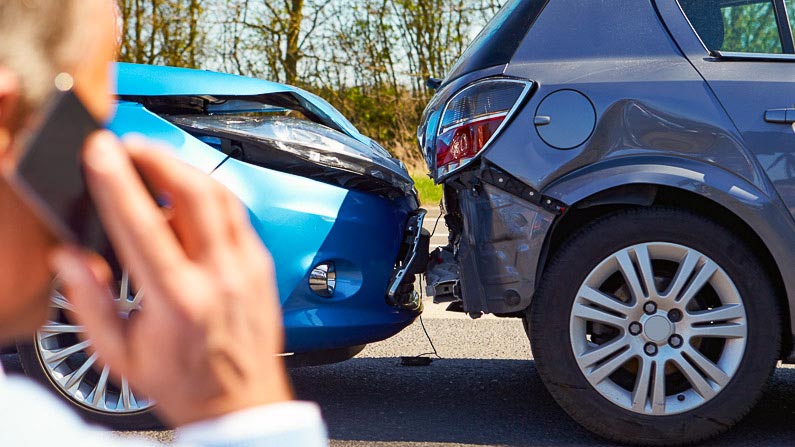 Zwei Autos nach einem Auffahrunfall mit Beschädigungen im Front- bzw. Heckbereich. Ein Mann telefoniert und ruft Hilfe.