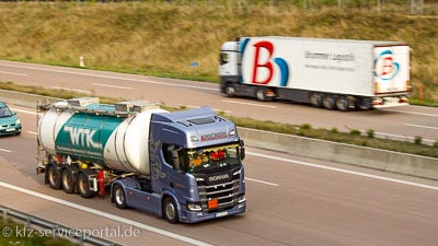 Zwei Nutzfahrzeuge fahren in unterschiedlichen Richtungen auf einer Autobahn.