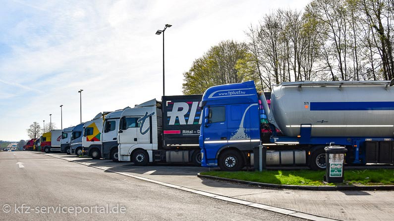 Auf einem Autobahnparkplatz stehen viele Lastkraftwagen.