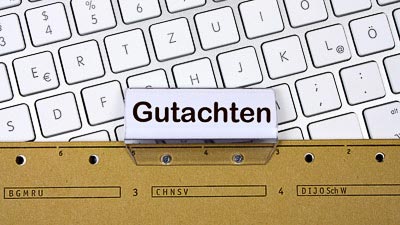 Eine Hängemappe mit der Aufschrift Gutachten liegt auf einer Tastatur.