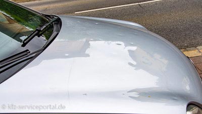 Auf einem PKW ist deutlich ein Hagelschaden auf der Motorhaube zu sehen