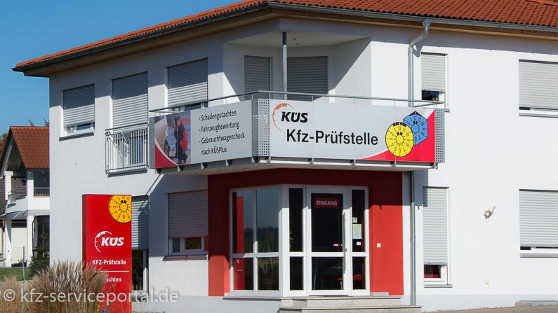 Eine KÜS Kfz-Prüfstelle mit einem Firmenschild davor.