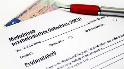 Ein Prüfungsprotokoll für die MPU ein Führerschein und ein Stift liegen auf einem Tisch.