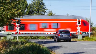 Ein Auto wartet an einem Bahnübergang, bis der Zug vorbeigefahren ist