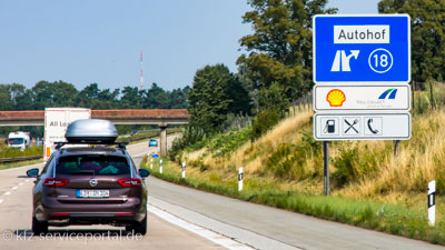 Ein Autobahnschild weist auf eine Tankstelle neben der Autobahn hin.