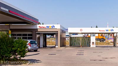 An einer Tankstelle ist eine Waschanlage und Waschboxen zu sehen.