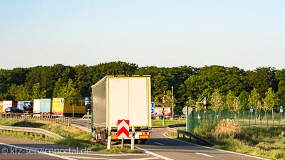 An einer Autobahntankstelle stehen viele Lastkraftwagen auf Parkplätzen.