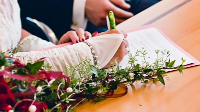 Eine Braut unterzeichnet den Ehevertrag.