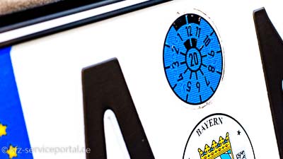 Auf dem Teil eines Nummernschildes ist die HU-Plakette zu sehen.