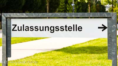 Ein Hinweisschild zeigt das Wort Zulassungsstelle mit einem Pfeil.