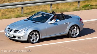 Ein silberner Mercedes Roadster Cabriolet fährt mit geöffnetem Verdeck. 