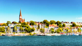 Flensburger Förde mit Segelschiffen und Hafen - im Hintergrund die St. Jürgen Kirche mit Wohnhäusern